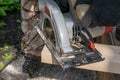 Man sawing a Board with a power tool, chips fly in all directions. Construction, wood processing