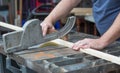 A man sawing through a piece of wood on a table saw.