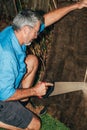 A man sawing a plank in the garden. Seasonal gardening. Repair work