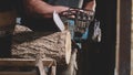 Man is sawing a wood with an electrical chainsaw at carpentry. Royalty Free Stock Photo