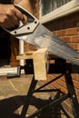 Man sawing wood outside using a hand saw Royalty Free Stock Photo