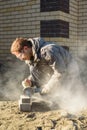A man saws off paving stones with an angle grinder. Street work