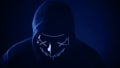 Man in scary lighting neon glow mask in hood in Phantom Blue color. Halloween and horror concept