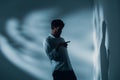 Man with schizophrenia standing alone in a room pointing at his shadow on the wall, real photo