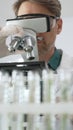Man scientific researcher in protective gear analyzing specimens through a microscope in a sterile laboratory Royalty Free Stock Photo