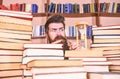 Man, scientist looks at hourglass. Time flow concept. Teacher or student with beard studying in library. Man on serious Royalty Free Stock Photo