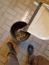 man scoops water into a bucket, with a dustpan from the flooded basement