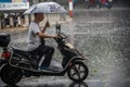 Man on scooter in tropical monsoon rain