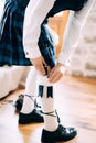 A man in Scottish national dress prepares for a wedding ceremony in a hotel room and putting sgian-dubh in kilt hose. Royalty Free Stock Photo