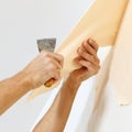Man in with a scraper in the process of removing old wallpaper. Royalty Free Stock Photo