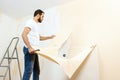 Man in with a scraper in the process of removing old wallpaper. Royalty Free Stock Photo