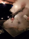 Man scrapes hot grill enveloped in rising cloud of steam