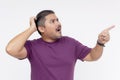 A man scratches his head looking stumped while pointing at something above and to the right. Wearing a purple waffle shirt.