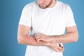 Man scratching forearm on color background. Allergy symptoms Royalty Free Stock Photo