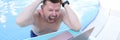 Man screaming and holding his hair and looking at laptop screen on side of pool Royalty Free Stock Photo