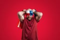 The man screams and blindfolds himself with an American flag. Red background. The concept of freedom, patriotism and protest