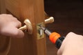 Man with a screwdriver in his hand repairs the inner door. door lock