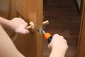 Man with a screwdriver in his hand repairs the inner door. door lock