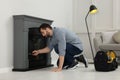 Man with screwdriver installing fireplace near wall in room Royalty Free Stock Photo