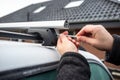 Man with a screwdriver installs attachments for trunk or cargo box on roof of the car