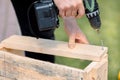 Man is screwing screw into wooden box with cordless screwdriver. Product repair with professional tool electric Royalty Free Stock Photo