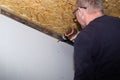 A man screws a drywall sheet to metal profiles with a screwdriver. Home renovation. Wall covering Royalty Free Stock Photo