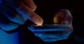 Man is scrolling display of smartphone, browsing internet at night, closeup view of fingers
