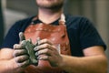 Man sculptor dressed leather apron with clay in hands. Statue craft creation workshop