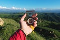 Man searching direction with a compass in his hand in the summer mountains point of view. Direction Search