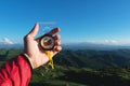 Man searching direction with a compass in his hand in the summer mountains point of view. Direction Search