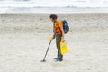 Man searching for a precious metal using a metal detector on a s