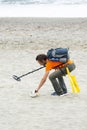 Man searching for a precious metal using a metal detector on a s