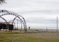 A man on the seashore next to an abandoned structure. Frame of rusty pieces of iron on the seashore