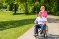 Man seated in wheel chair while wife pushes Royalty Free Stock Photo