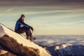 Man seating on top of mountain, male hiker admiring winter scenery on a mountaintop alone with ice ax