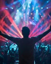 A man seen from back in a music event, dancing in neon color lights