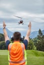 Man seen from behind instructing landing helicopter in the alps