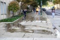 A man is seen power washing a city sidewalk with two girls walking around the area Royalty Free Stock Photo