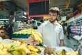 A handsome bearded man buys bananas in a supermarket. A man chooses fruit in the vegetable department