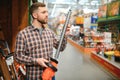 man selecting electric shears in salesroom of gardening tools shop Royalty Free Stock Photo