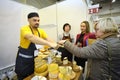 Man seller giving a woman buyer slice of cheese to taste it, cheese shop. Kyiv, Ukraine