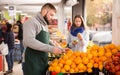 Man seller moving box of oranges in grocery shop Royalty Free Stock Photo