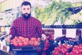 Man seller showing fresh tomatoes in vegetables shop