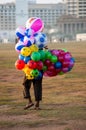 A man selling ballons of many different colors