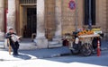 A Man selling fruit from a stall on a cart sits on the pavement in Nicosia Cyprus on a street corner reading a newspaper