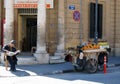 A Man selling fruit from a stall on a cart sits on the pavement in Nicosia Cyprus on a street corner reading a newspaper