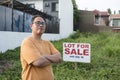 A man selling his undeveloped property inside a residential sudivision. An empty lot with a for sale sign