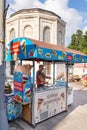 Man selling ice cream, or dondurma on traditional fast food cart with historical tomb in the background at Eyupsultan