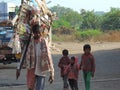 Man selling toys on the road with his children walking behind him