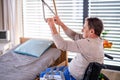 Man senior patient in wheelchair in hospital, holding onto a bed hanger.